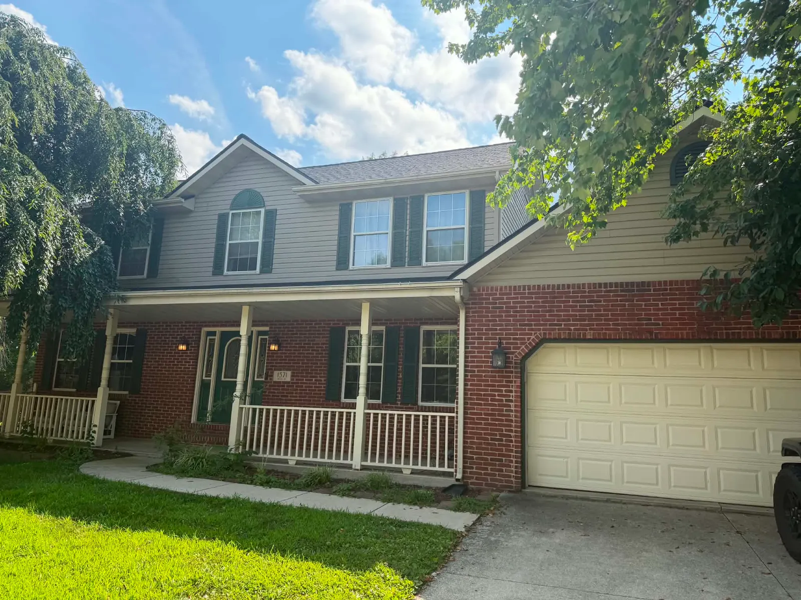 Two-story brick and siding home with a covered front porch and a new shingle roof